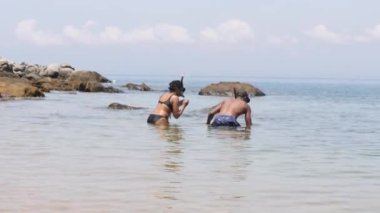 Yaz tatilinde bir çift büyük kayaların yanında birlikte denizde şnorkelle yüzüyor..