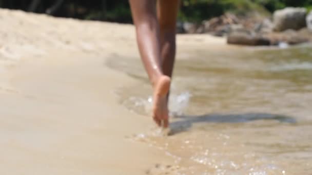 Yumuşak odaklı ve odaklanmış kadın bacakları kumlu sahilde su kenarında koşuyor.. — Stok video