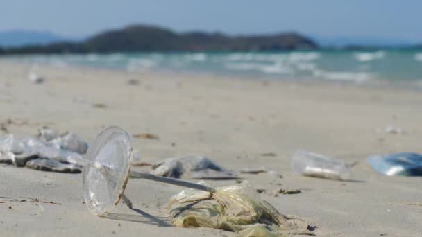 Plast och sugrör spolas bort och begravs i sanden på stranden. — Stockvideo