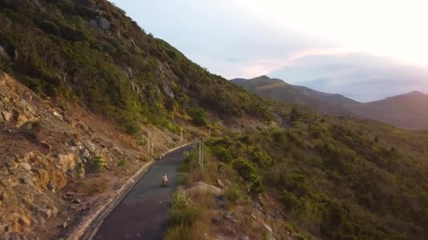 Seguimiento aéreo de un automovilista que viaja por el pintoresco camino de las montañas al atardecer. — Vídeos de Stock