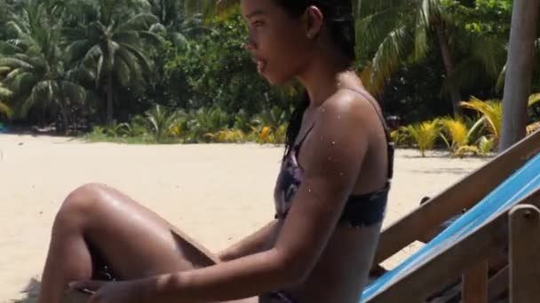Ung kvinna i våt bikini liggande på strandbänken, avkopplande och solbadande. — Stockvideo