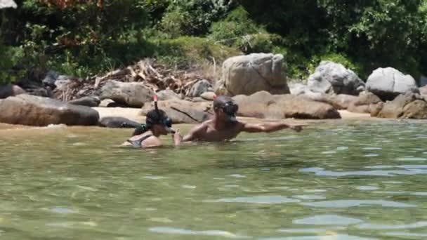 Couple plongée ensemble dans la plage tropicale avec de gros rochers en arrière-plan. — Video