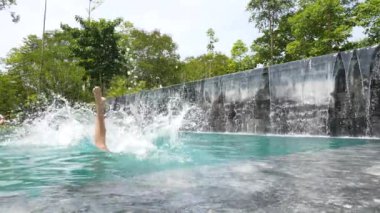 Yazın kısa atlayan bir adam açık havuzda suya atlıyor..