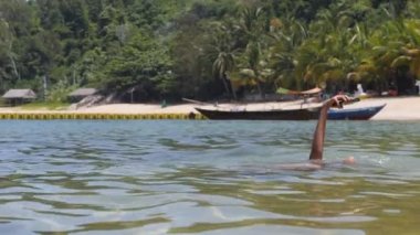 Kumsalda yıkanan genç bir kadın elinde akıllı telefonuyla selfie çekiyor..