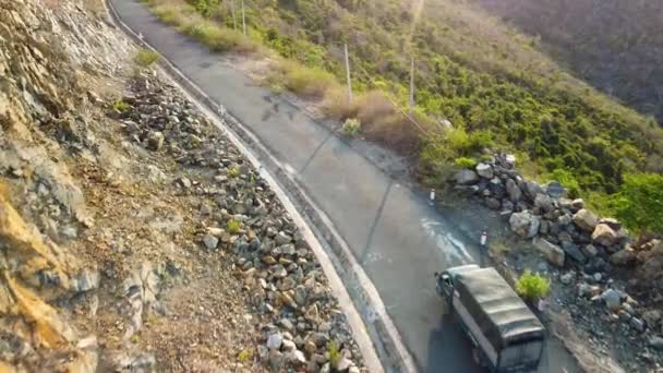 Suivi aérien du camion et de la moto voyageant sur la route de falaise de montagne. — Video