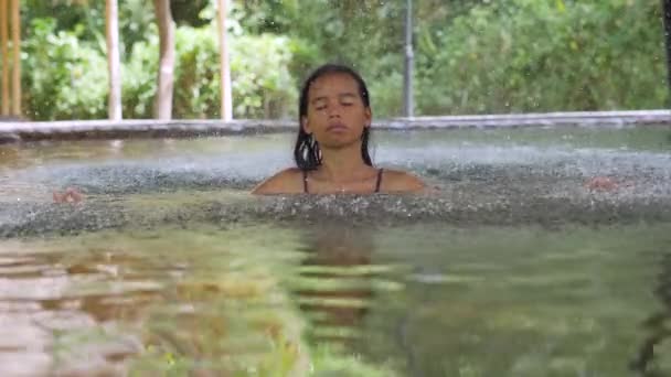 Ung kvinne med lukket øye og i zen positur avslappende i vann i svømmebasseng. – stockvideo