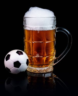 Bardak bira ve bir siyah arka plan üzerine izole bir küçük futbol topu.