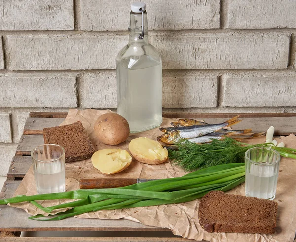 Traditional Ukrainian and Russian snacks outdoor. Food with alcohol. Vodka and smoked fish with bread, dill, jacket potatoes and bunching onion. — Stock Image Traditional Ukrainian and Russian snacks outdoor. Food with alcohol. Vodka and smoked fish with bread, dill, jacket potatoes and bunching onion. Stock Photo