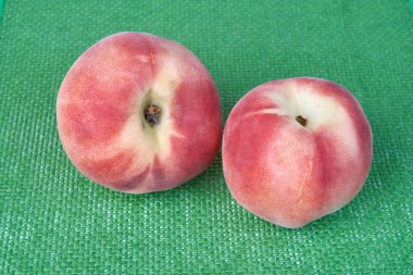 Olgun lezzetli şeftali meyve yeşil hasır kumaş üzerine.