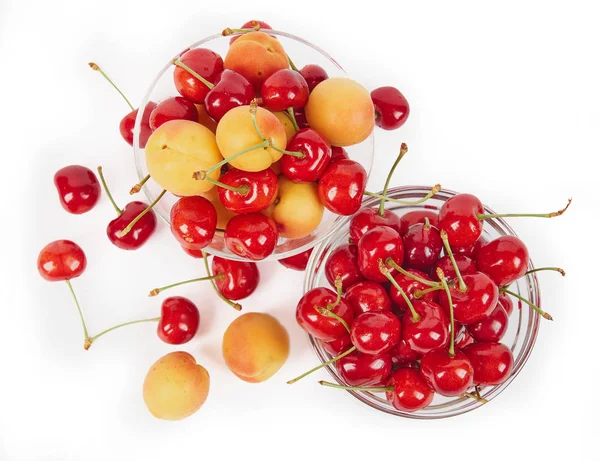 Viele reife frische Aprikosen und Kirschen in einer Glasvase isoliert auf weißem Hintergrund — Stockfoto