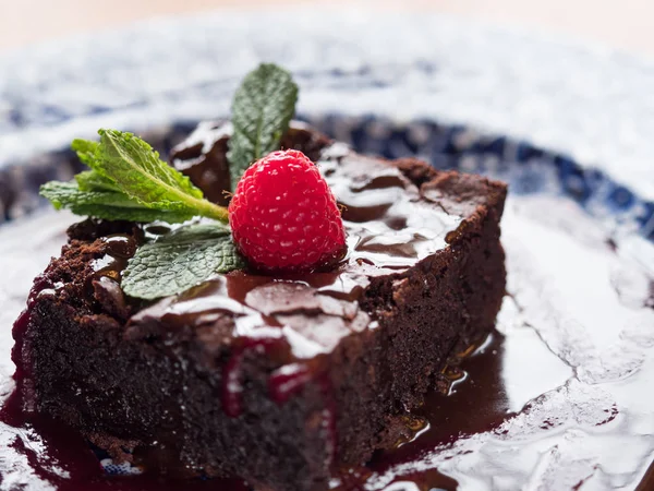 Chocolate cake with raspberry and mint leaf.