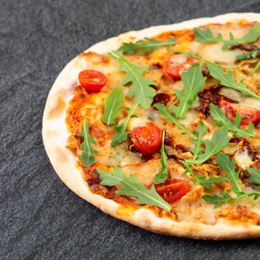 Masada vişneli domates ve roka ile sulu pizza.