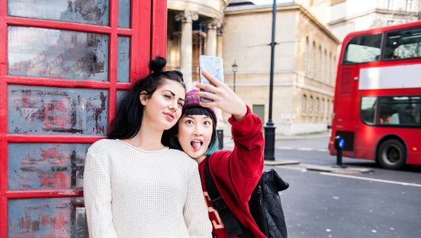 Dos Mujeres Jóvenes Elegantes Tomando Selfie Por Cabina Del Teléfono — Foto de Stock