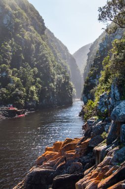 Bir grup insan Kano içinde uzak arka plan üzerinde Deep river gorge doğa yatay.