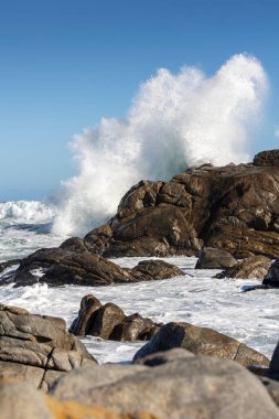 Büyük Okyanus Dalgası Kayaya Karşı Çarpıyor Deniz 'in Su Sıçratan Gücü Açık Mavi Gökyüzü ve Rocky Sahil Hattı altında