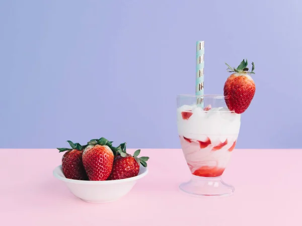 Milkshake with straw and strawberry.