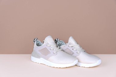 Atış bej renkli arka plan üzerinde altın spor ayakkabı.