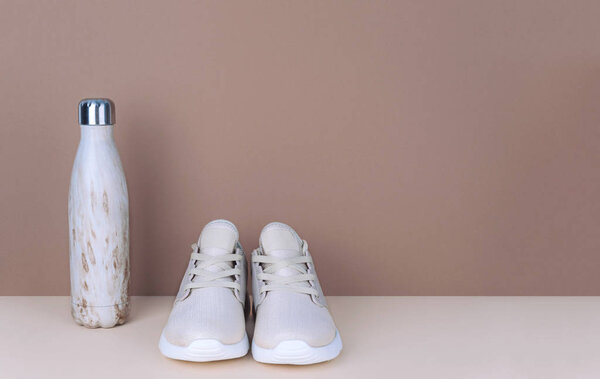 Shot of golden sneakers on beige background. Stylish healthy lifestyle concept.
