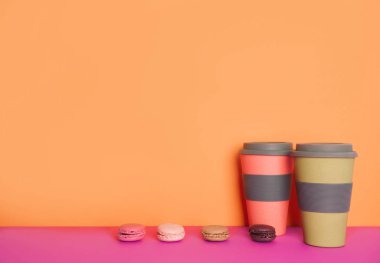 Metniniz için yer ile sarı ve pembe arka plan üzerinde macaron ile kahve fincan.