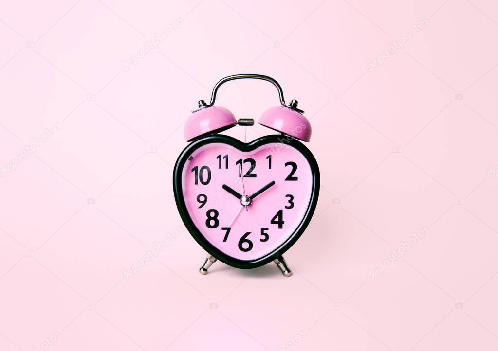 Heart shaped clock on pink background.