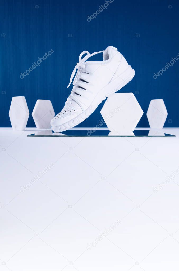 Pair of white sneakers on blue and white background.