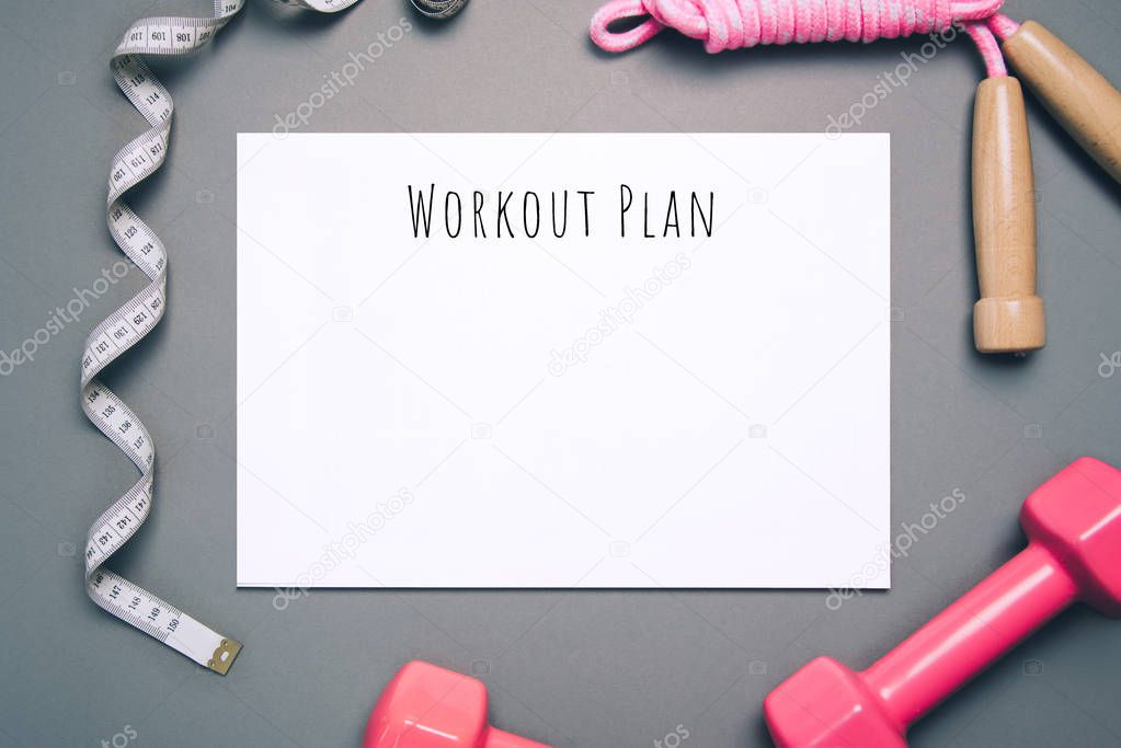 Flat lay shot of workout plan on gray background.