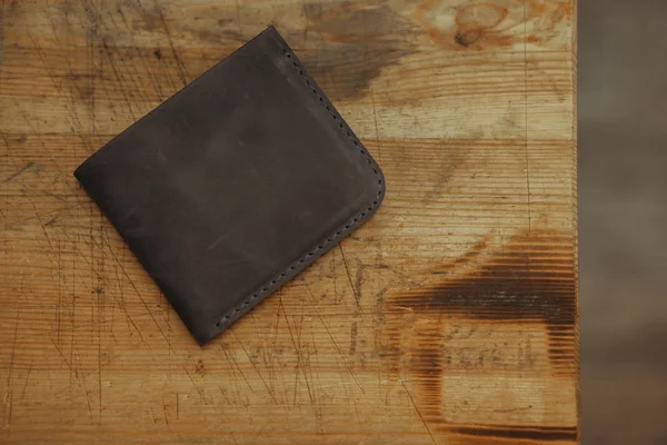 Black leather wallet on wooden background. Top view. Handmade leather wallet