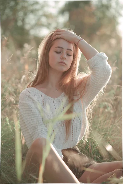Porträtt av snygg tjej som sitter i fält — Stockfoto