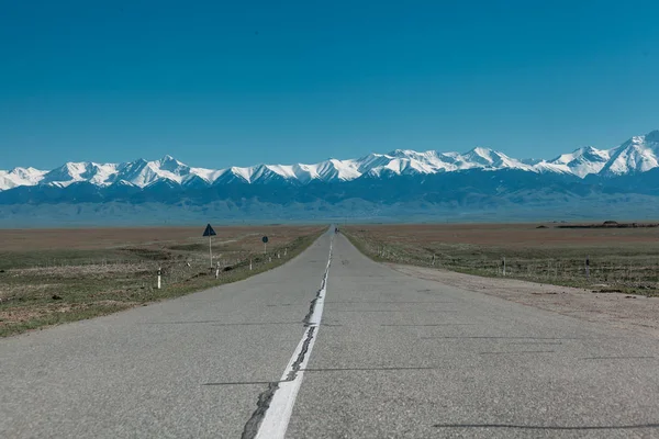Karlı dağlara ve mavi gökyüzüne giden yol