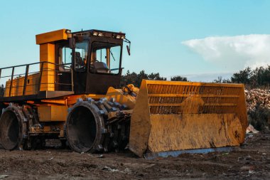 Kirli zeminüzerinde çalışan büyük sarı traktör
