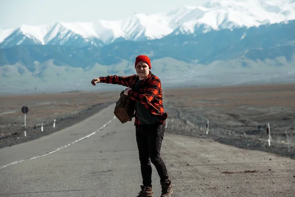 Hipster in red hitchhiking on old dusty road