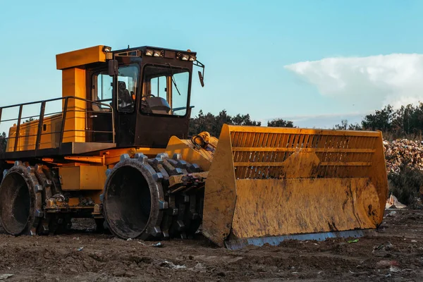 Kirli zeminüzerinde çalışan büyük sarı traktör