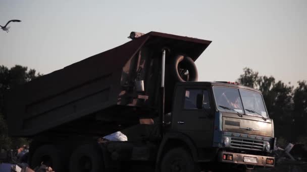 Grand camion russe déchargeant du gravier gris dans les rayons du coucher du soleil — Video