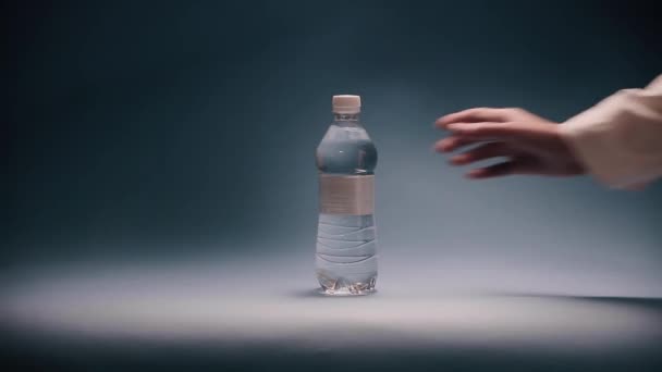 Рука положить бутылку воды в луч света — стоковое видео