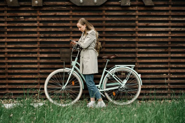 Junge Frau mit Fahrrad vor Holzwand — Stockfoto