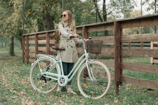 Frau hält Ruder ihres Fahrrads an Zaun — Stockfoto