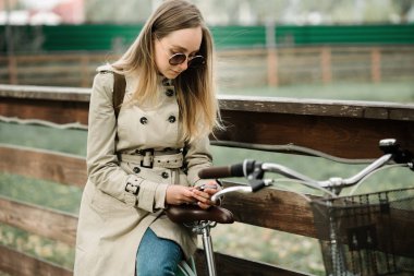 Telefonuna bakan paltolu kız çitlere yaslandı