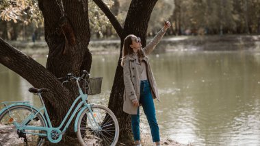 Bir ağacın altında bisiklet ile silfie yapıyor Kız