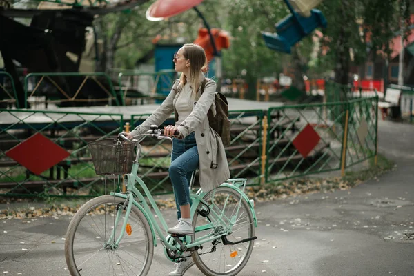 Menina jovem livrando na bicicleta através do parque de diversões — Fotografia de Stock