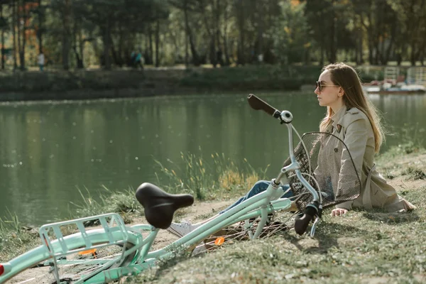 Flicka som sitter nära sjön i höst parken — Stockfoto