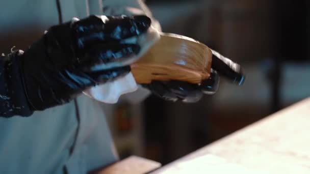 Крупним планом жіноча рука в захисній рукавичці лакує дерев'яну поверхню в майстерні. Спеціальне лакове покриття. Концепція столярної роботи та обробки столярних виробів — стокове відео