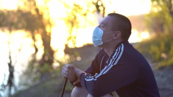 Adam yüzünde tıbbi maskenin altındaki dumanı salıyor. — Stok video