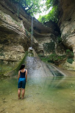 kız ormanda bir uçurumdan düşme geri yüksek bir şelale önünde ayakta
