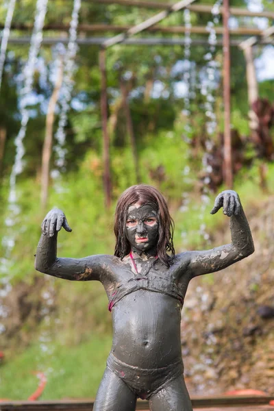 girl in a swimsuit in a mud mask on the whole body depicts a zombie