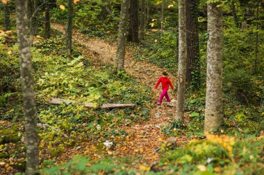 Kırmızı elbiseli kız sonbahar orman ile iz üzerinde olduğunu