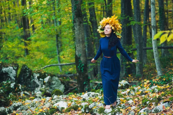 秋天森林里那个穿着蓝色衣服的女孩闭着眼睛站着 她戴着黄叶花圈 — 图库照片