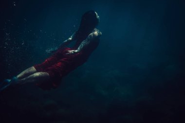 brunette girl in long red dress dives underwater clipart
