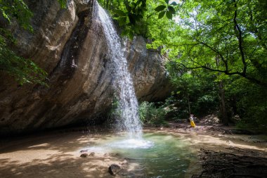 esmer kız sarı etek ayakta yakındaki taşkın kırma yüksek şelale kayalar