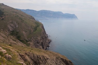 yüksek kayalık bir sahil üzerinde bir yol ve denize yelken bir tekne
