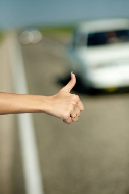 yakın çekim bir kadının eli ile yükseltilmiş başparmak hitchyürüyüş araba